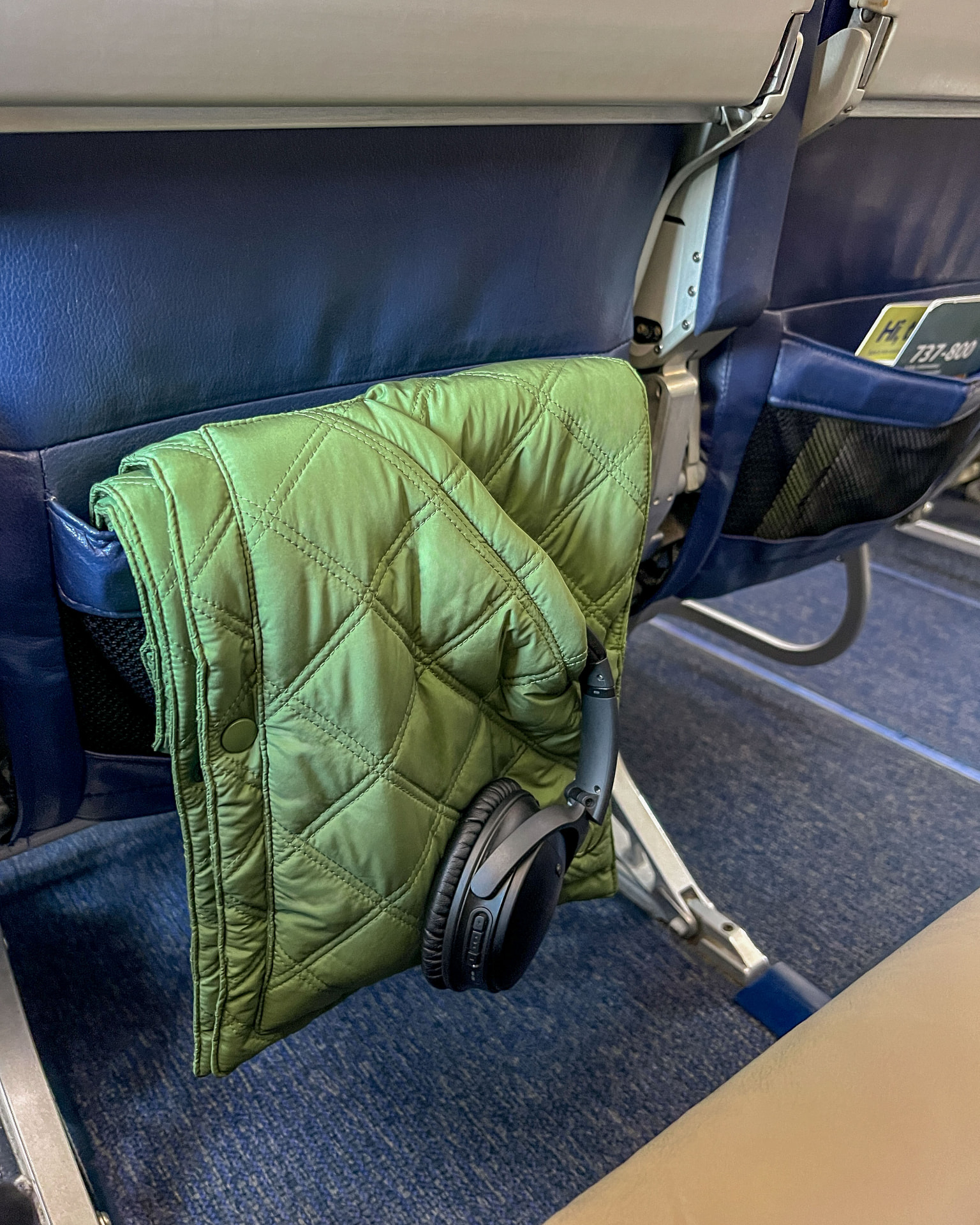 Green 418 Scarf with headphones on an airplane seat