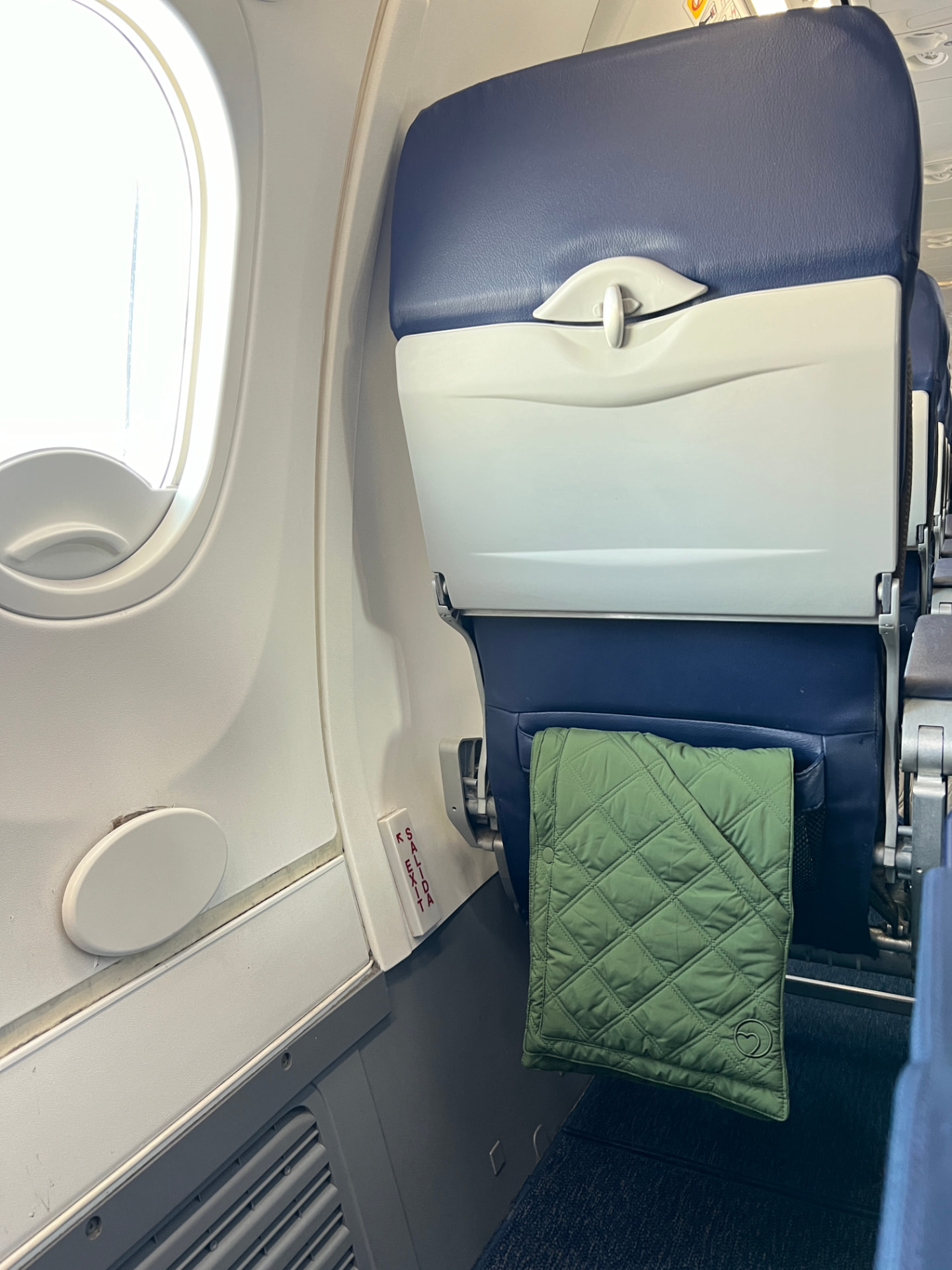 Green 418 Scarf hanging on an airplane seat by the window